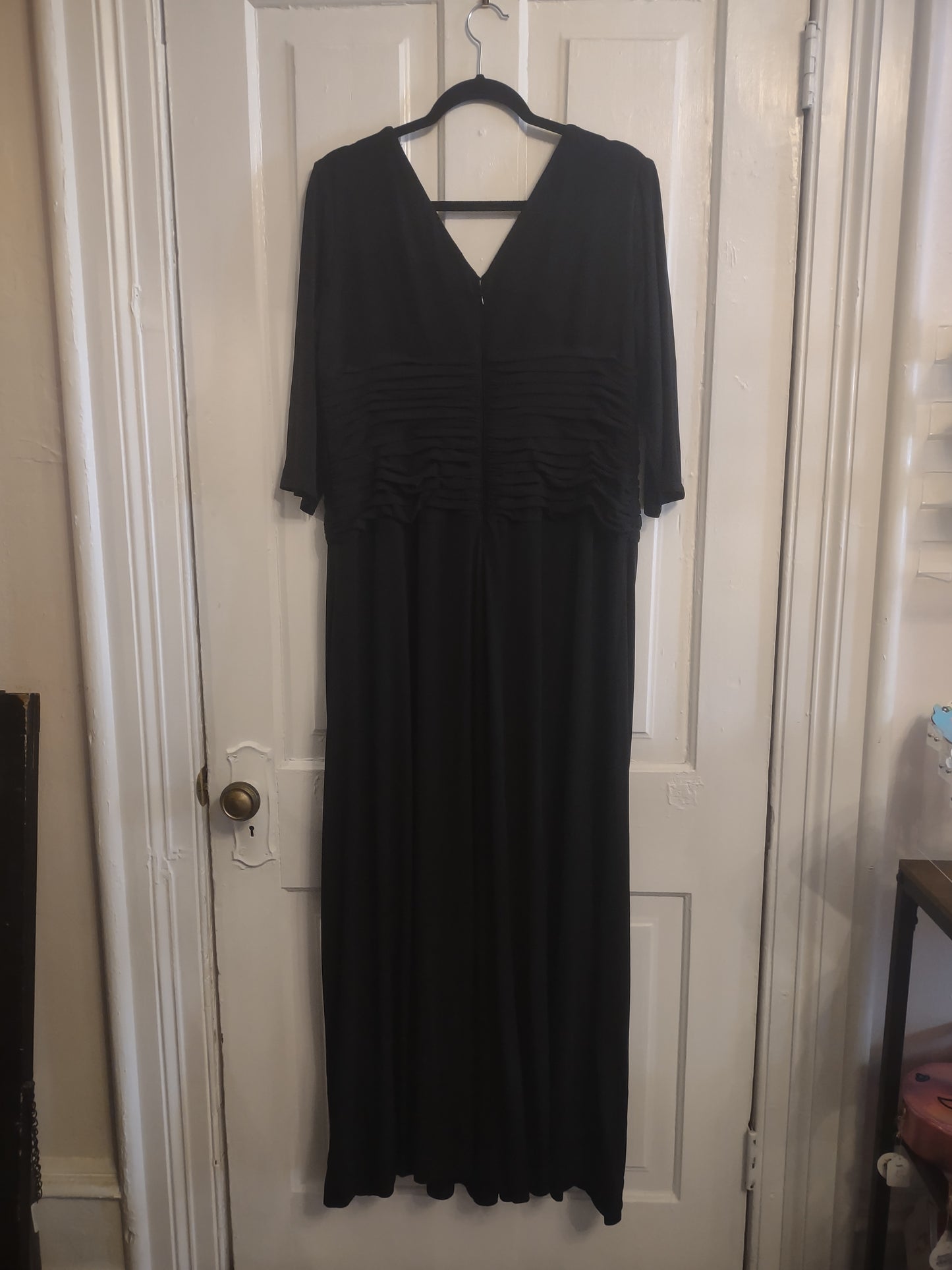 Black dress on a hanger against a white door background