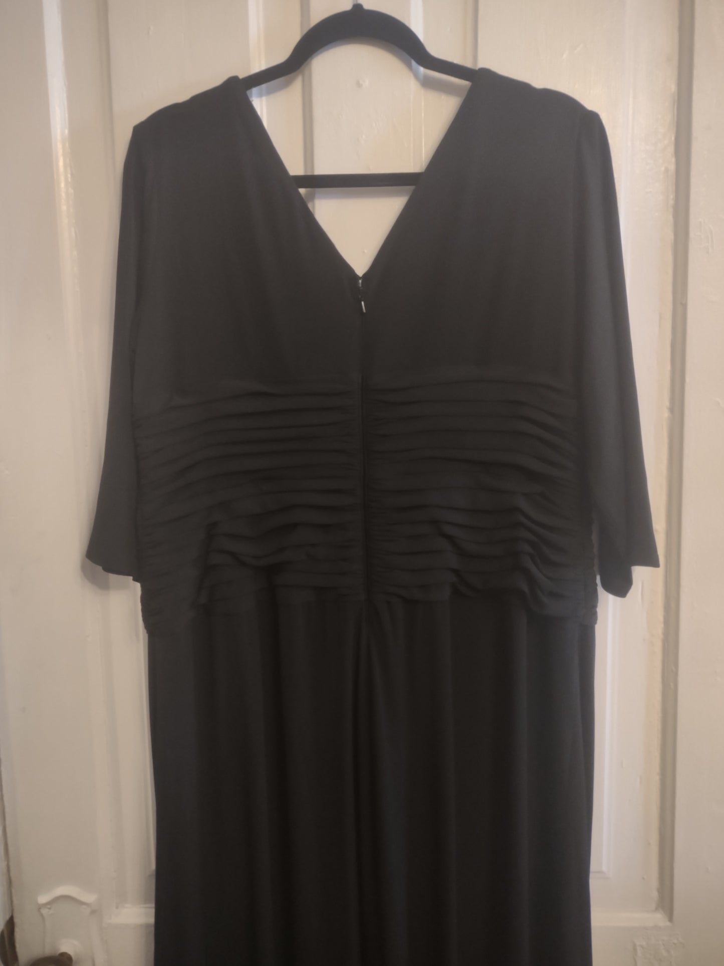 Black dress on a hanger against a white door.