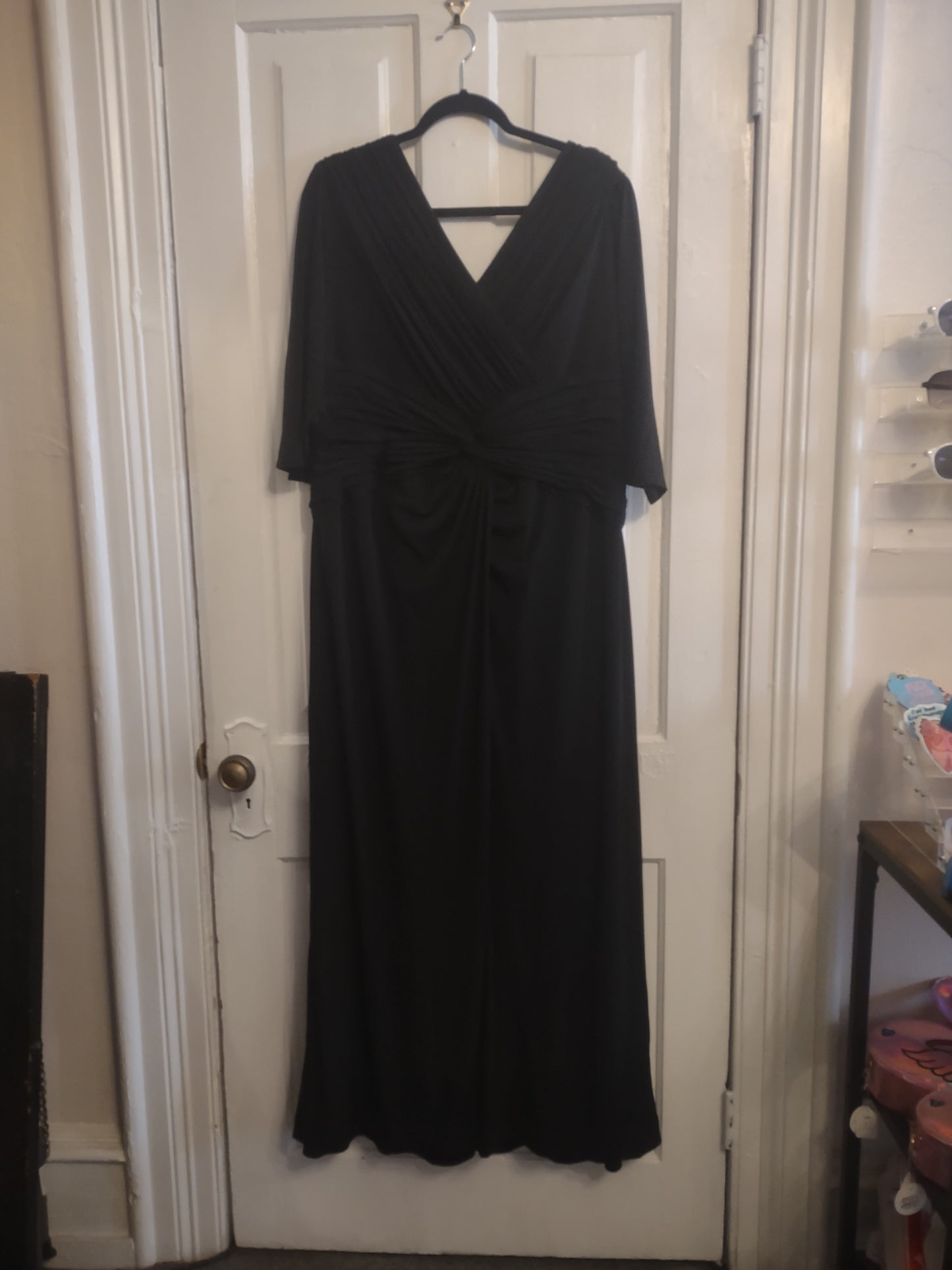 Black dress on a hanger in front of a white door.
