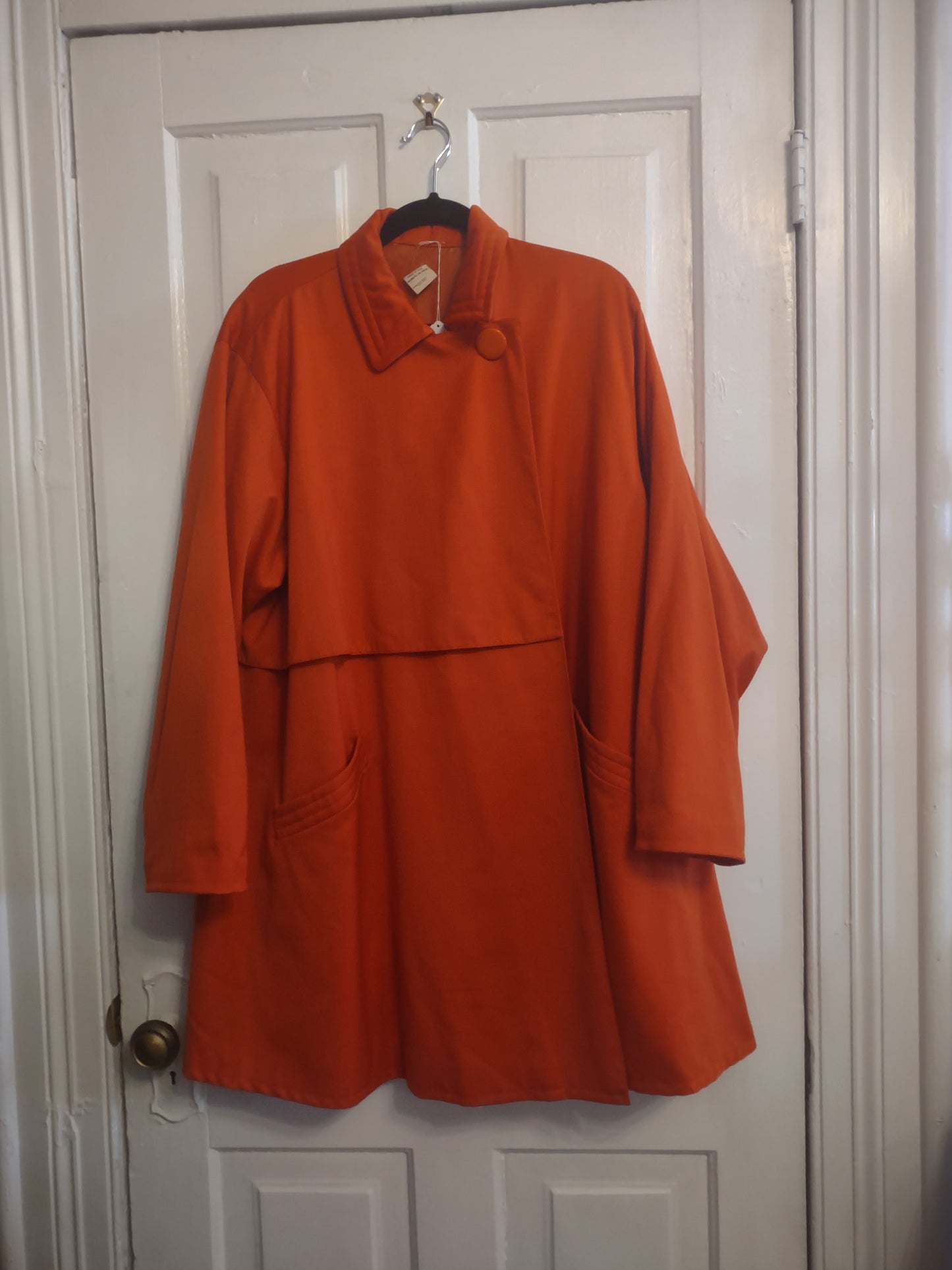 Orange jacket on a hanger against a white background