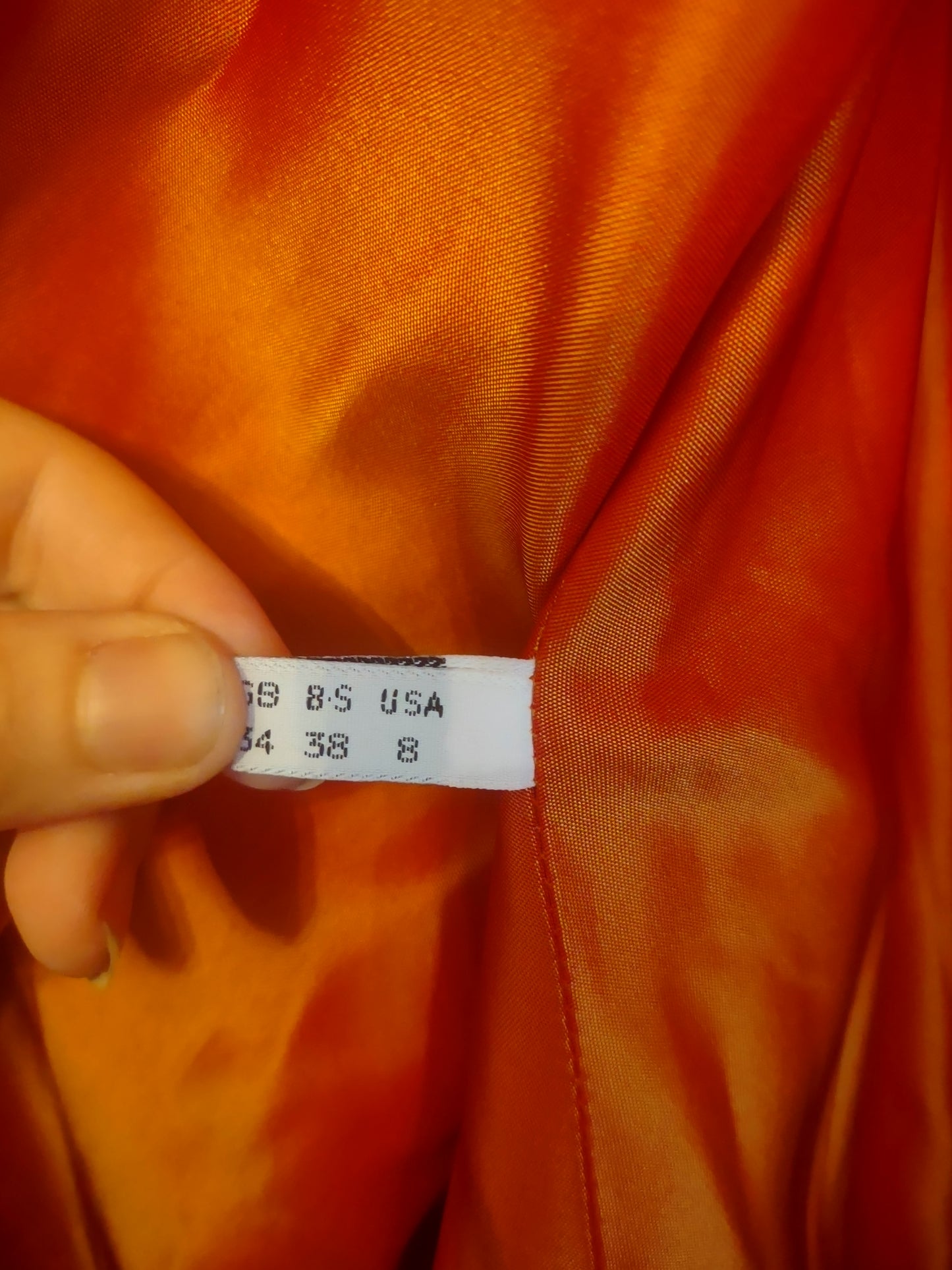 Close-up of a clothing tag on an orange Satin background