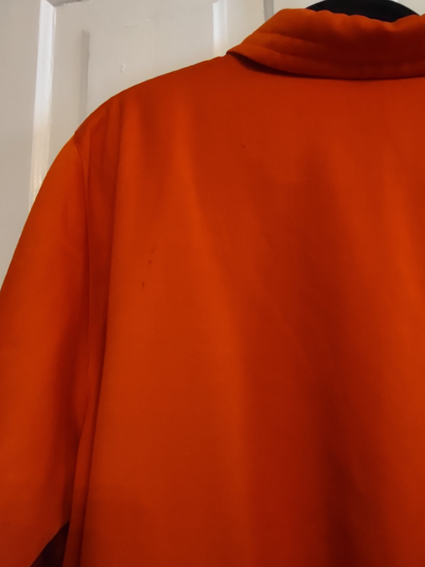 Close-up of orange fabric with a blurred background. Two small snags visible.